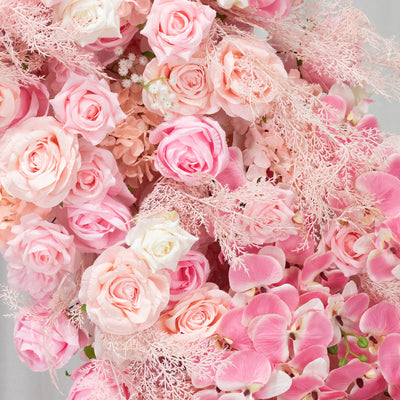 Pink floral arrangement featuring roses and orchids in soft hues.