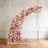 Flower arch arrangement in soft pink hues against a white background.