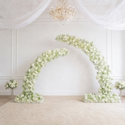 Elegant white floral wedding arch in a bright chandelier venue