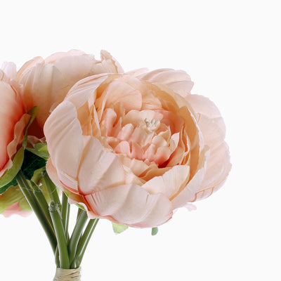 Peach artificial peony bouquet on a plain backdrop
