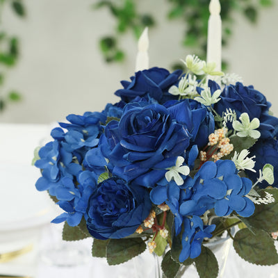 Blue floral arrangement with roses and greenery in a glass vase.