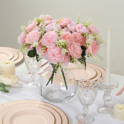 Pink peony flower arrangement in a glass vase on a dining table.