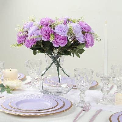 Purple bouquet in glass vase on elegant dining table setting.