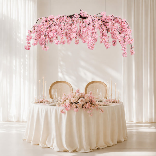 Elegant blush pink floral wedding table with cherry blossom canopy under soft drapes