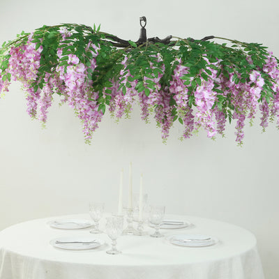 Hanging floral chandelier with purple wisteria above a dining table setting.
