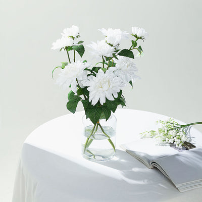 White flower bouquet in a glass vase on a table with a magazine.