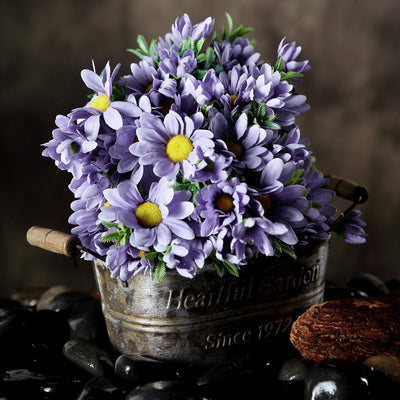 Purple daisies in a rustic metal planter on a stone surface.