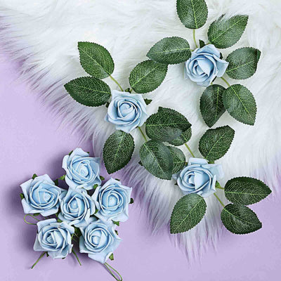 Blue artificial roses with green leaves arranged on a purple background.