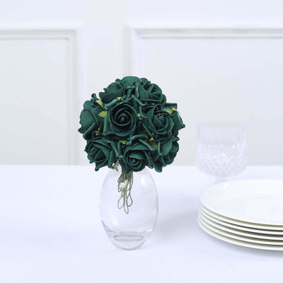 Green fabric rose bouquet in a glass vase on a table.