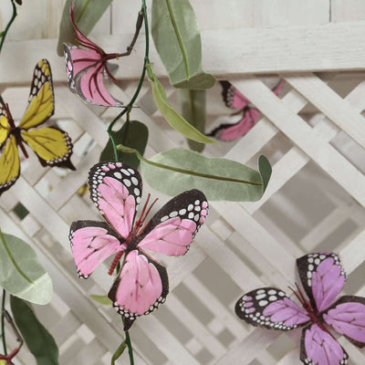Colorful butterfly garland decoration with green leaves on a trellis backdrop.