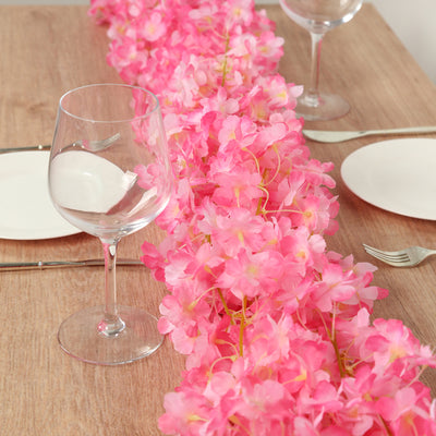 Pink floral table runner with wine glasses and plates set for dining.
