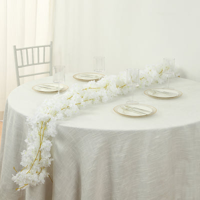 Elegant white floral centerpiece on a dining table with glassware and plates.