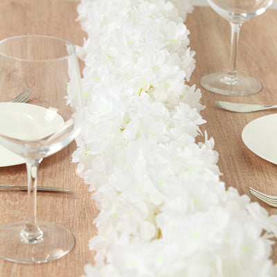 White floral table runner with plates and glasses set for dining.