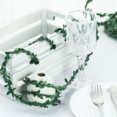 Decorative table setting with greenery, glassware, and white crate.