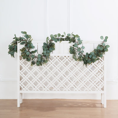 White decorative trellis with greenery accents on a plain backdrop.