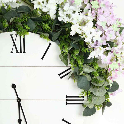 Floral wall clock with greenery and flowers, featuring Roman numerals.