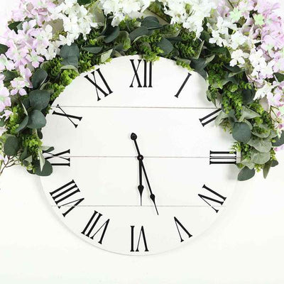 Floral wall clock with Roman numerals and greenery accents.