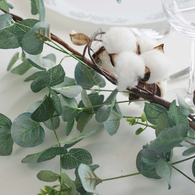 Cotton branch and eucalyptus leaves arranged elegantly on a table setting.