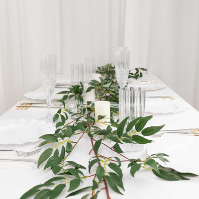 Elegant dining table set with greenery and crystal glassware.