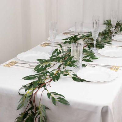 Elegant dining table set with greenery, plates, and crystal glassware.