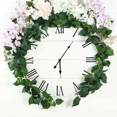 Floral wall clock with green leaves and pink flowers, elegant home decor.
