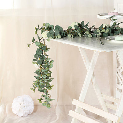Green leafy garland on a white table with soft fabric backdrop.