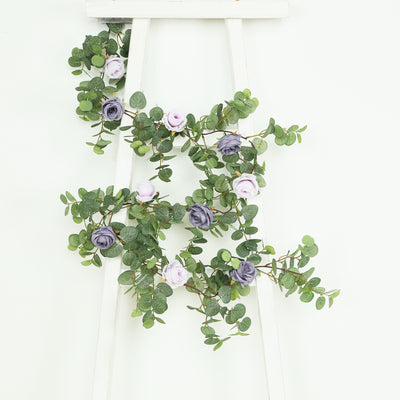 Artificial floral garland with purple and pink roses on a white background.