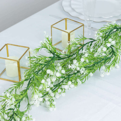 Artificial floral garland with white flowers on a table setting.