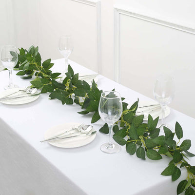 Table setting with greenery, plates, and glassware for a stylish dining experience.