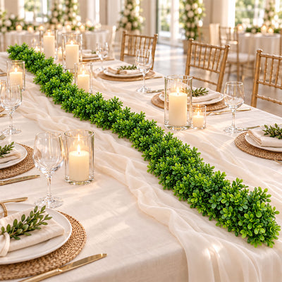 Elegant wedding reception table with candles, greenery, and gold chairs