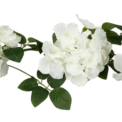 White floral garland with lush green leaves on a plain background