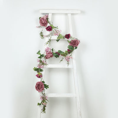 Artificial floral garland draped on a white wooden ladder