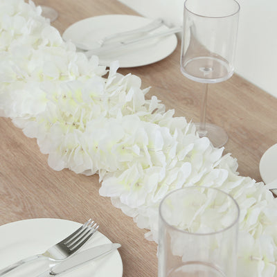 White floral table runner on a wooden table with plates and glassware.