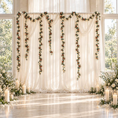 Elegant wedding backdrop with ivory drapes, floral garlands, and candle decor