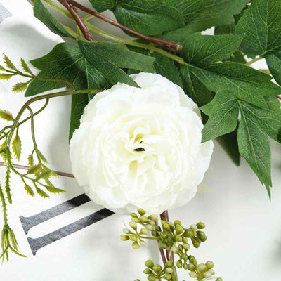 White floral decoration with green leaves on a light background.