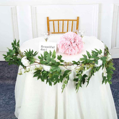 Table centerpiece with pink flowers and greenery, decorated for an event.
