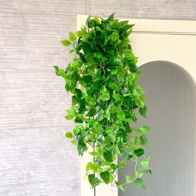 Artificial green vine plant with lush leaves hanging decoratively.