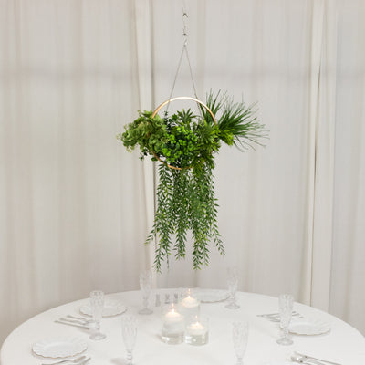 Hanging greenery centerpiece over a dining table with candles.