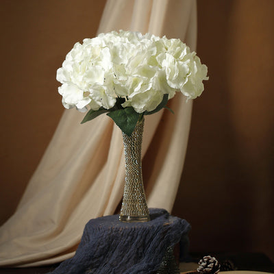 White hydrangea bouquet in a decorative vase on a rustic table.