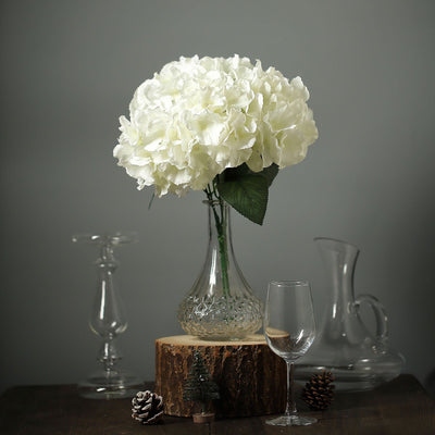 White hydrangea bouquet in a glass vase with rustic decor elements.