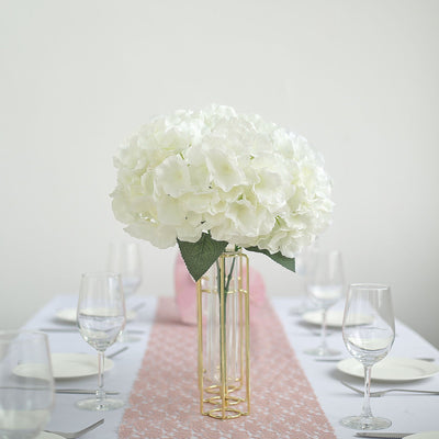 White hydrangea bouquet in a gold vase on a dining table setting.