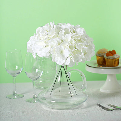 White hydrangea bouquet in a glass vase on a table with drinks and desserts.