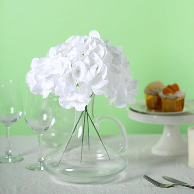 White flowers in a clear vase on a green background.