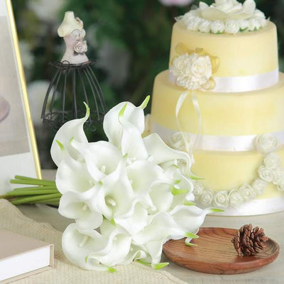 White calla lily bouquet with decorative cake and vintage decor in the background.
