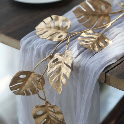 Gold monstera leaf decor on a table with a white drape.