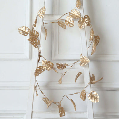 Gold leaf garland decor hanging on a white ladder.