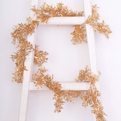 Gold leaf garland draped on a white ladder.