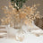 Gold leaf branches in a clear vase on a dining table setting.
