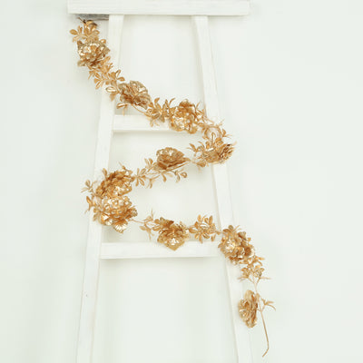 Gold floral garland draped on a white ladder