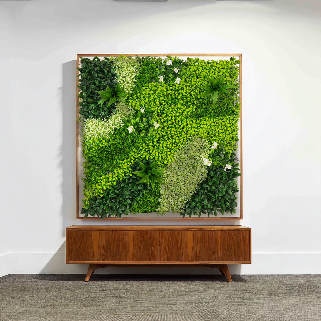 Artificial green wall art in a wooden frame above a mid-century modern console.